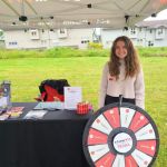 Communications Specialist Kelly Furey attending Hats Off Day in Burnaby on June 18. Communications Specialist Kelly Furey attending Hats Off Day in Burnaby on June 18. She is standing behind E-Comm's trivia wheel and presenting our brochures and merchandise.